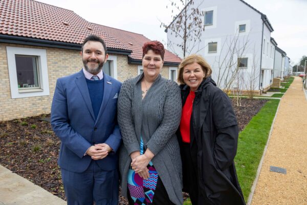 three people in front of some new homes