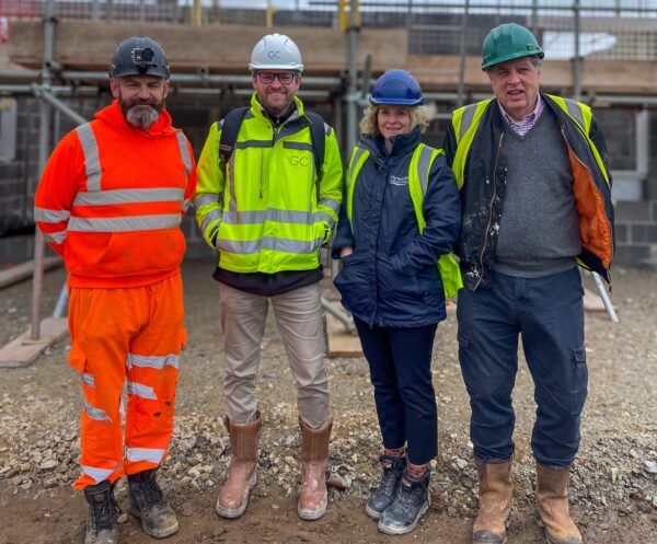 4 People in hi viz and hard hats standing on a homes building site