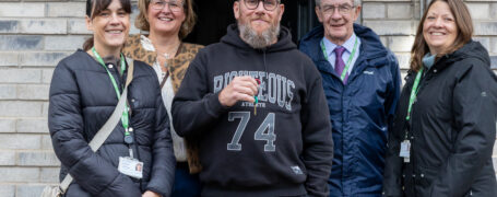 5 People in front of a house with a man holding keys in the centre